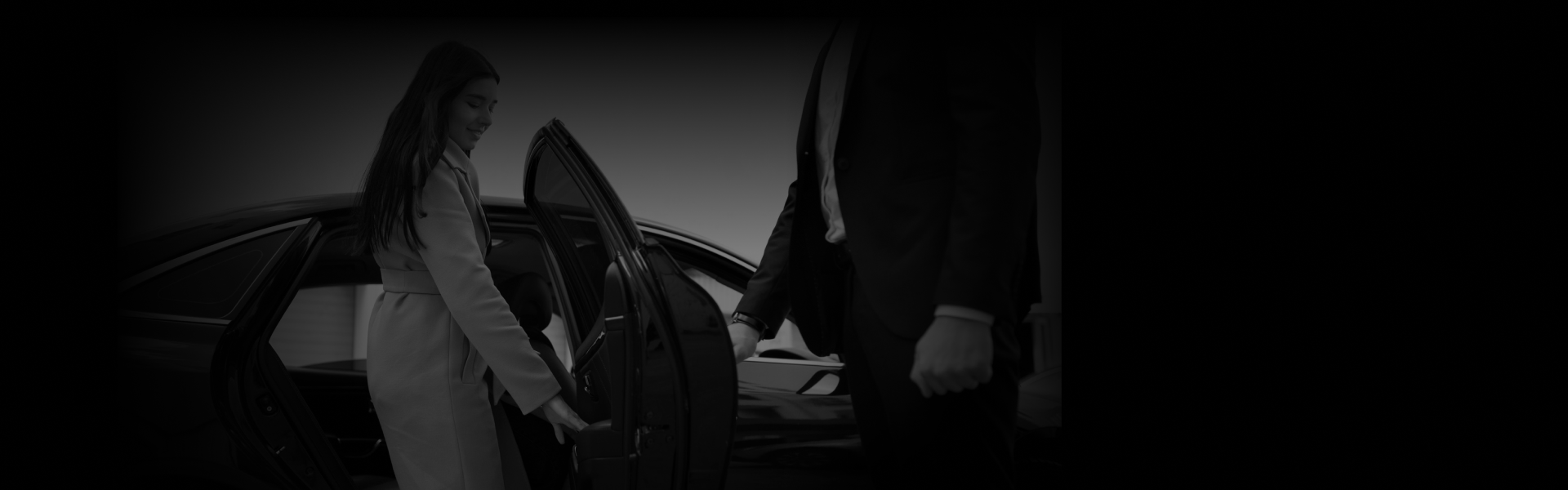 A woman steps into a sleek black car as a suited chauffeur holds the door open, showcasing premium Chauffeur Service in NYC from a side-angle view.