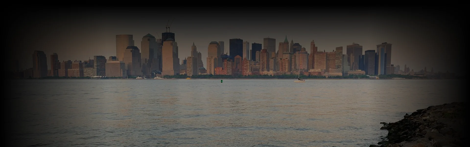 Overhead view of a luxury black sedan as a chauffeur assists a man in a beige coat—capturing a premium New York to Greenport transfer moment.